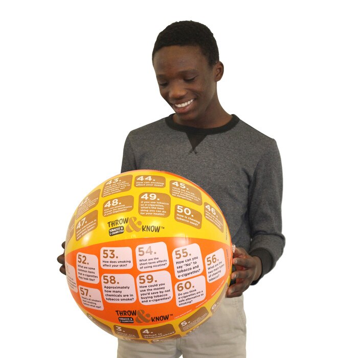 Teenage boy holding and reading Health Edco's Tobacco and E-Cigarettes Throw & Know Activity Ball for health education, 78828