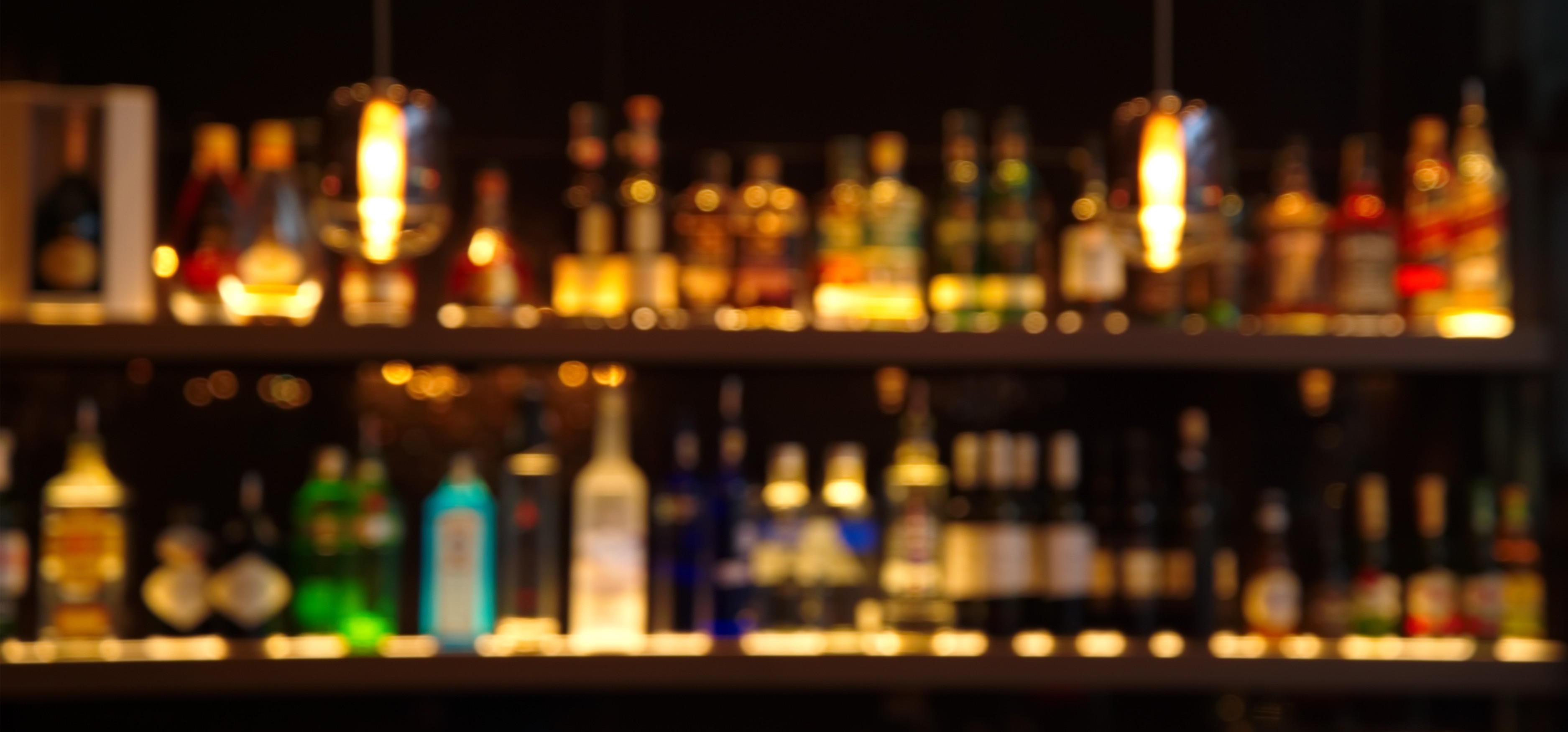 colorful alcohol bottles behind a dark bar