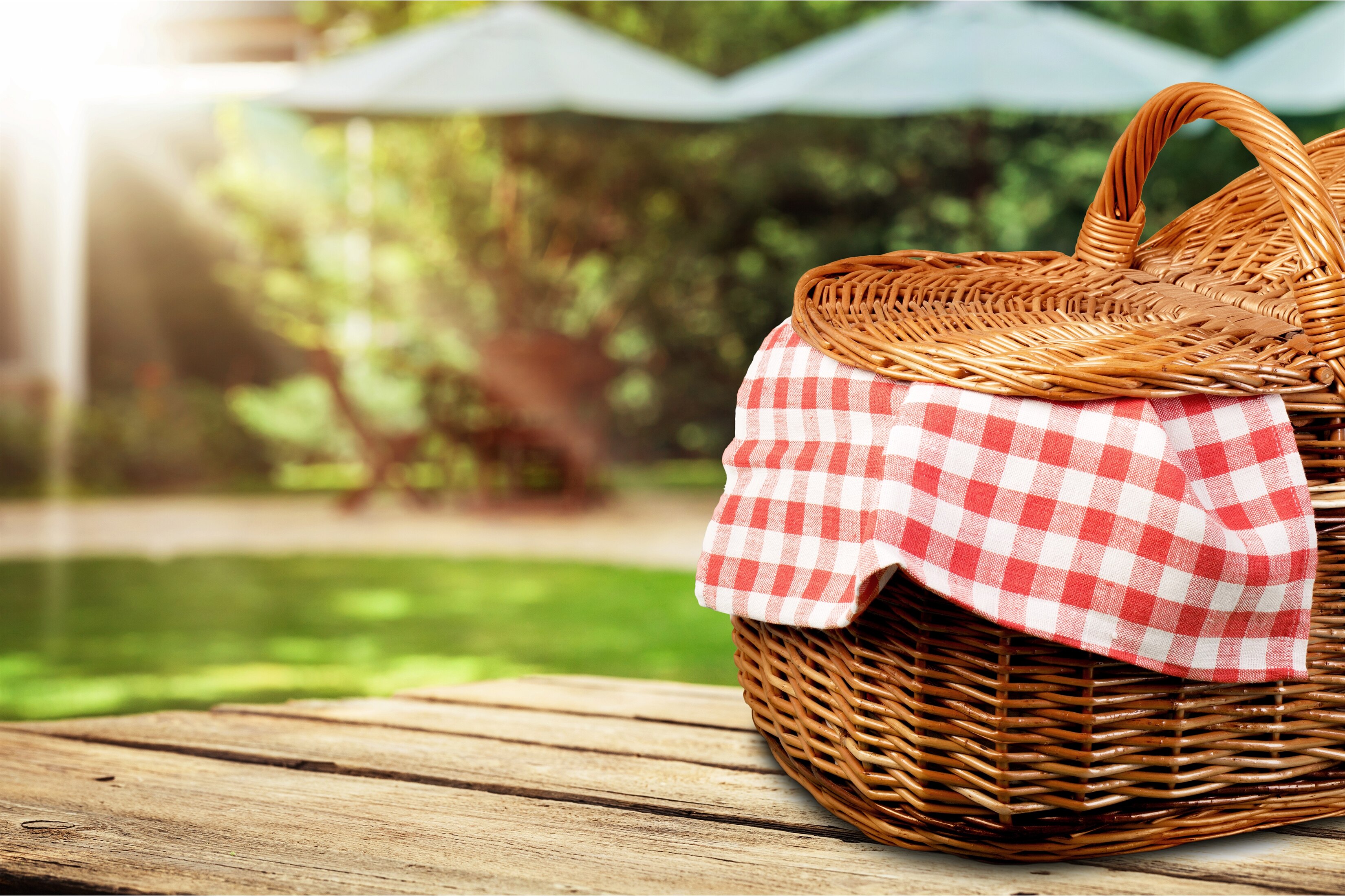 Picnic basket on a table with sun-shading umbrellas in the background